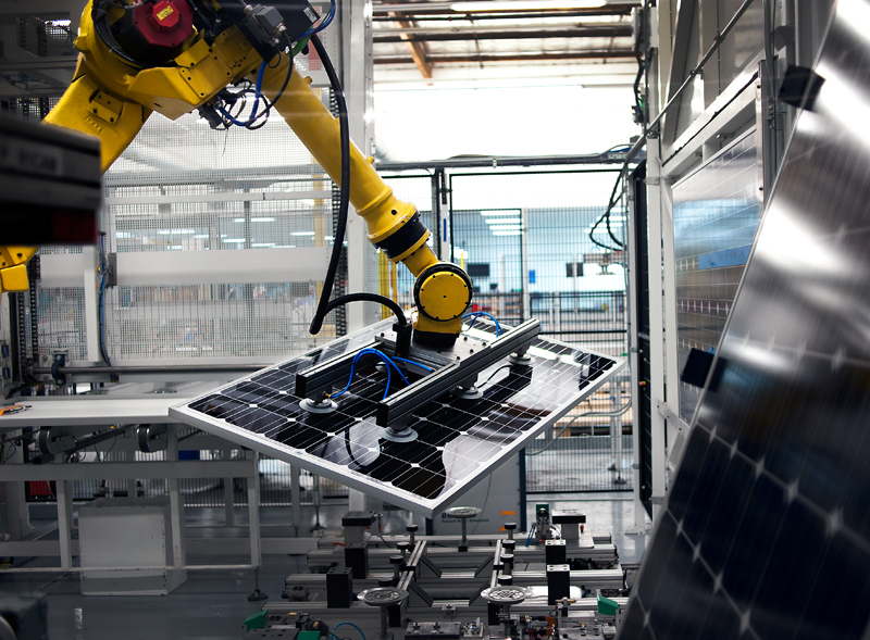A robotic arm manipulates a solar panel during the manufacturing process. 